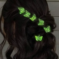 Set of six glowing butterfly hair clips in green fluorescent finish on wavy dark hair - Luminous
