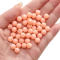 Matte peach acrylic round beads for DIY jewelry held in hand showing hole detail - Creamy Green