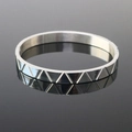 Close-up of silver steel cuff bracelet with textured triangle patterns and polished finish - Engraved Triangle Bangle Silver