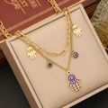 Close-up of gold double-layered necklace featuring Hamsa Hand and Evil Eye charms on jewelry box - Necklace (Style 1)