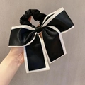 Detailed close-up of a large black satin bow hair tie with elegant white contrast piping - White Edge / Black