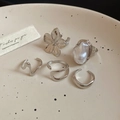 Detail view of 5-piece silver floral and pearl ring set on a beige ceramic plate - Silver Pearl 5-Piece Set