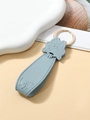 Detail of light blue PU leather pig keychain with golden metal ring on soft background - Light Blue