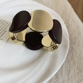 Detail of broad gold and chocolate acrylic chunky stretch bracelet on white ceramic tray - Oval Style / Gold Brown