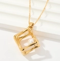 Détail du pendentif carré doré avec perle blanche sur fond texturé blanc moderne - Perle Géométrique