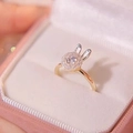 Dettaglio macro di un anello a coniglio dorato rotante con zircone in scatola di velluto rosa - Anello Coniglio Oro