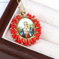 Close-up of Bohemian religious medal necklace with red beads in a wooden jewelry box - Red