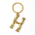 Close-up of a gold metal letter H keychain with a circular ring on a white background - Letter H