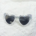 Close-up of heart-shaped bride sunglasses with iridescent rhinestones on white lace - Half Rhinestone Heart Glasses
