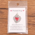 Silver pocket hug heart pendant with red enamel on a rustic wooden background - Vintage Textured Red Heart