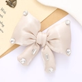 Close-up of beige satin fabric bow with sparkling rhinestone inlay for DIY hair accessories - Off White