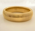 Detail of golden Tubogas wide bracelet with ribbed texture on reflective surface - 20mm Gold
