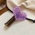 Close-up of a purple acrylic heart banana clip with yellow stitching detail on a fabric background - Purple
