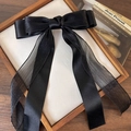 Detail of a large black chiffon bow hair clip with long ribbons on a wooden tray - Black Bow
