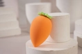 Makroaufnahme von karottenförmigem orange-grünem Make-up-Schwamm auf weißem Sockel - Orange Karotte