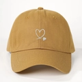 Detail of white heart embroidery on a mustard yellow cotton baseball cap with twill texture - One Size / Turmeric