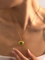 Détail d'un collier en acier titane doré avec un pendentif rond en pierre précieuse verte - Pierre d'Œil de Chat Verte