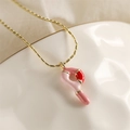 Détail d'un collier chaîne dorée avec pendentif abstrait émaillé rose et rouge sur céramique - Style-P