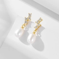 Vista macro dettagliata di eleganti perle a goccia e zirconi su base dorata - Argento 925 / Oro