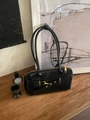 Sac bowling rétro en cuir noir avec ferrures dorées sur surface en bois - Noir