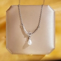 Collier élégant en acier titane avec nœud et perle goutte sur boîte à bijoux - Perle de Nœud d'Argent