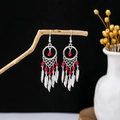 Detail of bohemian silver dreamcatcher earrings with red beads and hanging metal feathers - Red