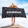 Detail of a large zebra print microfiber beach towel with white SUMMER lettering at the sea - Zebra Summer
