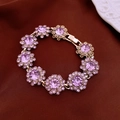 Detalle de una pulsera floral dorada con grandes cristales morados y diamantes - Pulsera Morada