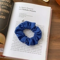 Detail of navy blue pleated scrunchie with From Sheep label on an open book - Sapphire Blue