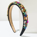 Détail d'un serre-tête baroque avec cristaux multicolores exposé sur un support blanc - Coloré