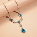 Macro d'un collier vintage argenté avec un pendentif goutte bleue et des cristaux fins - Collier / Bleu