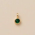 Close-up of gold pendant featuring a round-cut emerald green zircon on textured paper - Round May Pendant (Emerald Green)