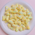 Close-up of yellow butterfly beads with iridescent finish in a white ceramic bowl - Yellow