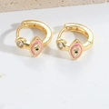 Detailed view of gold hoop earrings featuring pink and black eye motifs and clear stones - Pink