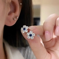 Detailed macro shot of a silver flower stud earring with a blue central zircon stone - Silver Earring Post - Silver - Blue