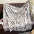 Primer plano de bufanda de seda gris con patrones de camelias sobre un sofá de cuero - 90cmx90cm / Gris (XW-197-Gris)
