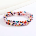 Macro shot of three colorful beaded elastic waist chains on a clean white fabric background - Rainbow