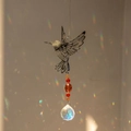 Hummingbird crystal suncatcher with colorful beads reflecting rainbows on a wall - Hummingbird