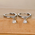 Detail of silver hoop earrings with clear round cubic zirconia charms on wood base - Silver White Zircon