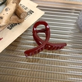 Dettaglio di una molletta per capelli rosso bordeaux su una superficie di vetro decorativa - Stile a Forma di U (A)