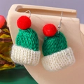 Close-up of handmade mini knitted hat earrings in festive red and green with soft textures - Green