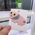 Rosa gestrickte Schweinchen-Haarspange für Mädchen mit grauem Schal auf weißer Karte - Energetisches Schwein
