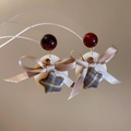 Detail of star earring with plaid fabric pendant, red bead and champagne ribbon bow - Brown