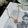 Detail shot of a golden square pendant with letter Z resting on a lifestyle magazine - Letter Z