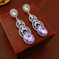 Macro shot of silver drop earrings with purple and clear crystals on a brown leather box - Silver Pin Water Drop Style / Purple/Silver