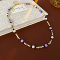 Dettaglio di collana con perle, perline viola e nere su trama di lino - Collana-Viola-Nero
