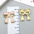 Pink enamel bow pendant with gold finish next to a ruler for size reference - KC Gold Pink Hollow Bowknot