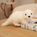 Niedliche Plüsch Seeotter Puppe in weißer Farbe liegend auf einem Holzschreibtisch - Weiß / 33CM