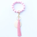 Porte-clés bracelet en perles de bois roses avec pompon en cuir et anneau doré sur blanc - Rose