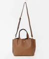 Detail of caramel brown PU tote bag featuring round handles and golden logo hardware - Light Brown